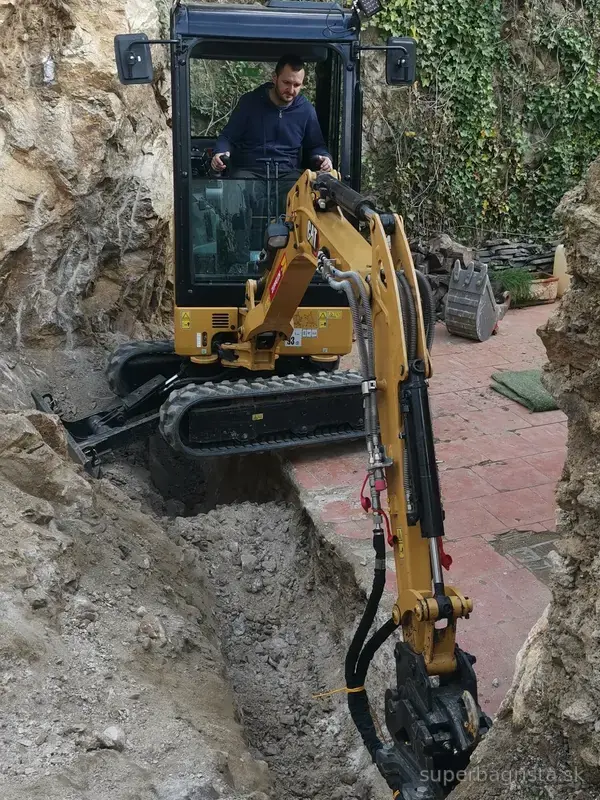 Kompaktný minibáger CAT s kladivom v úzkom skalnom výkope
