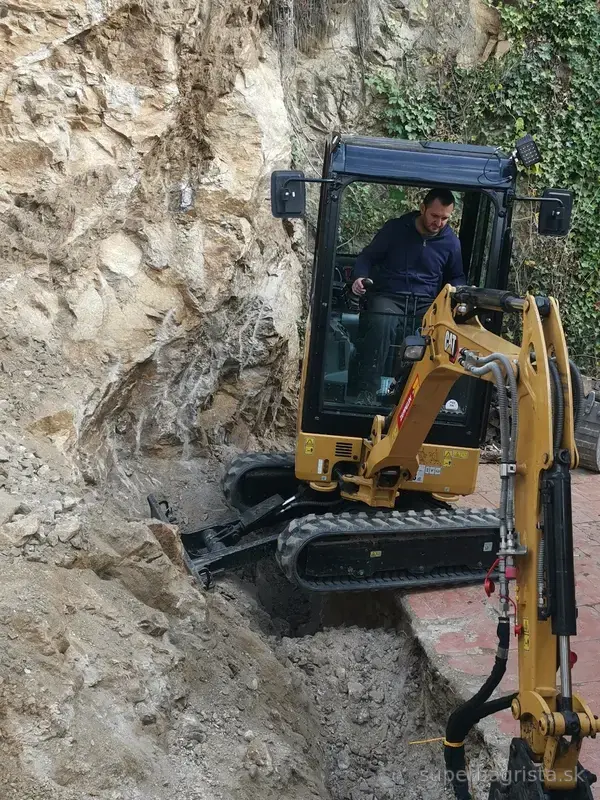 Hydraulické kladivo na minibagri CAT pri prehlbovaní ryhy v skale
