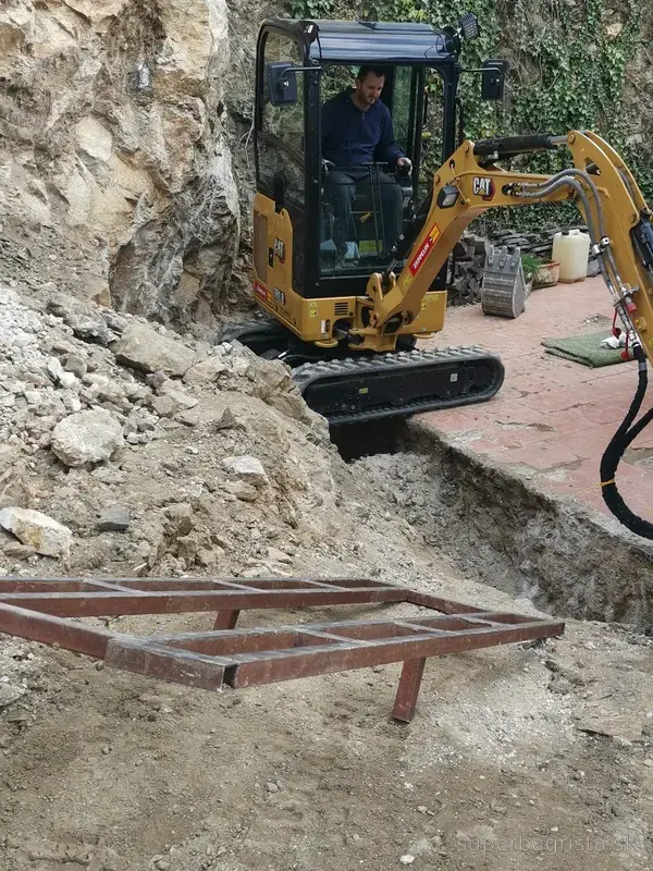 Minibáger CAT pri odstraňovaní rozbitej skaly