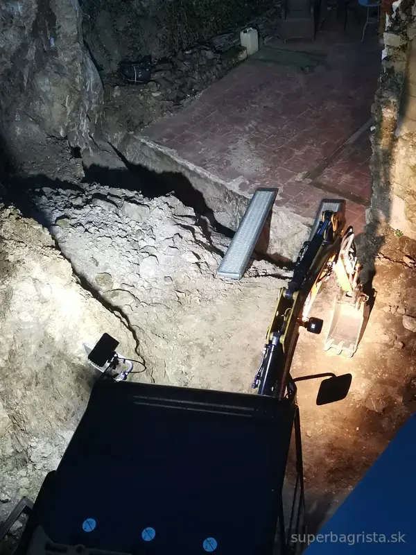 Večerné vyberanie rozbitej skaly z výkopu minibagrom CAT