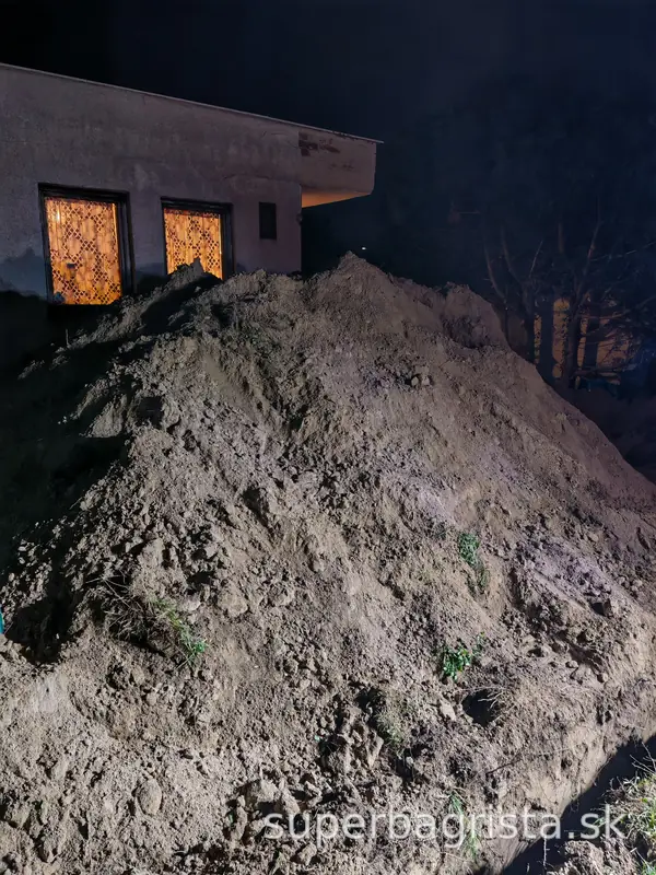 Vyťažená zemina z jamy pre zbernú nádrž pri večernej práci