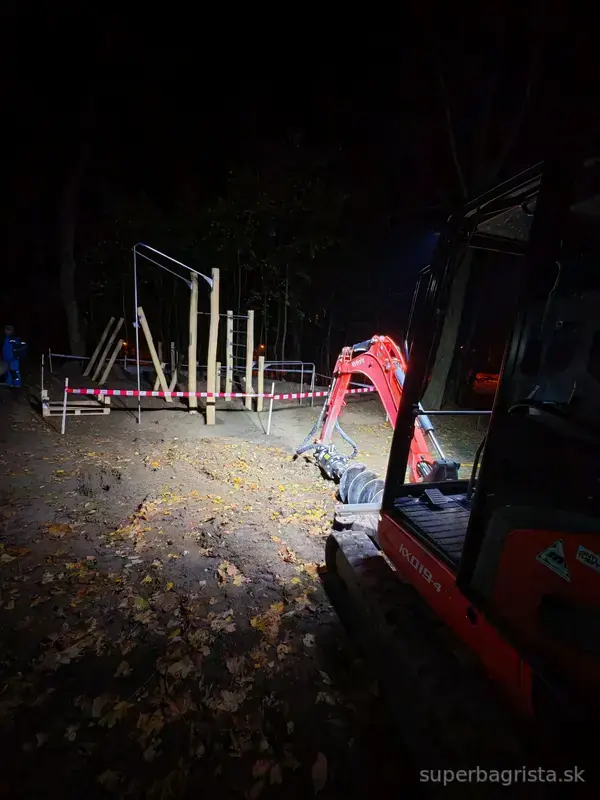 Minibáger Kubota so zemným vrtákom pri večernej práci
